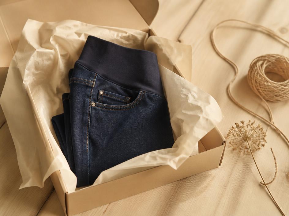 Gefaltete Umstandsjeans in Seidenpapier in einem Paket aus Kraftpapier